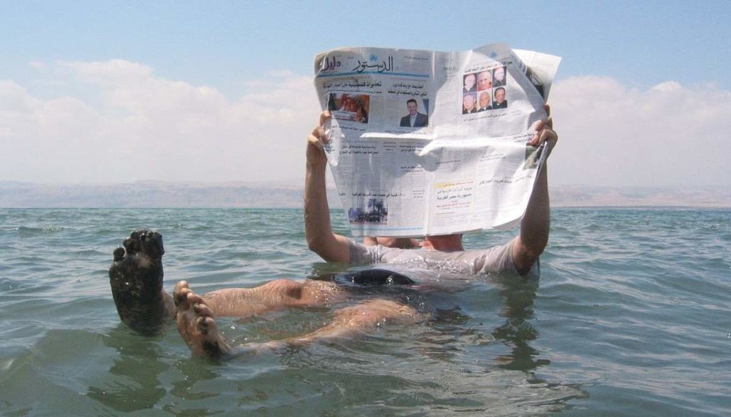 Reading newspaper in the Dead Sea